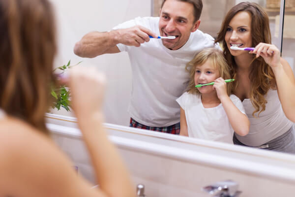 Porodica pere zube i gleda se u ogledalu