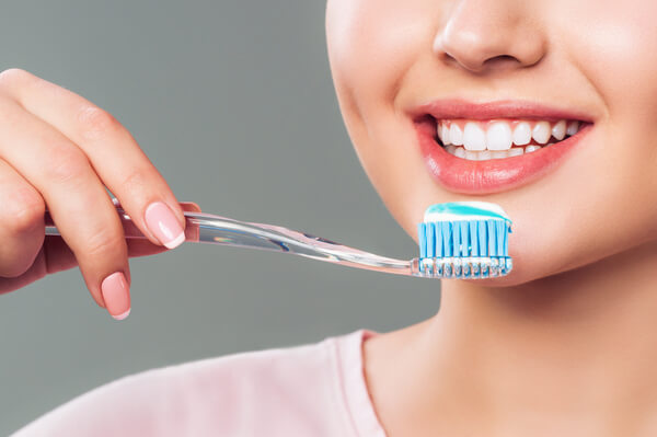 Zenska osoba drzi cetkicu za zube sa pastom pre pranja zuba